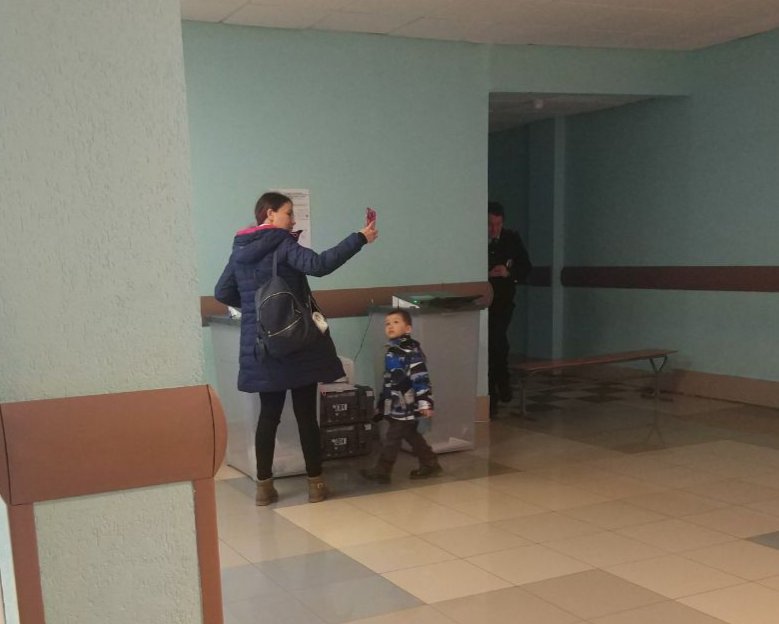 Женщина фотографируется с бюллетенем рядом с урной для голосования. Фото: «Наблюдатели Петербурга»