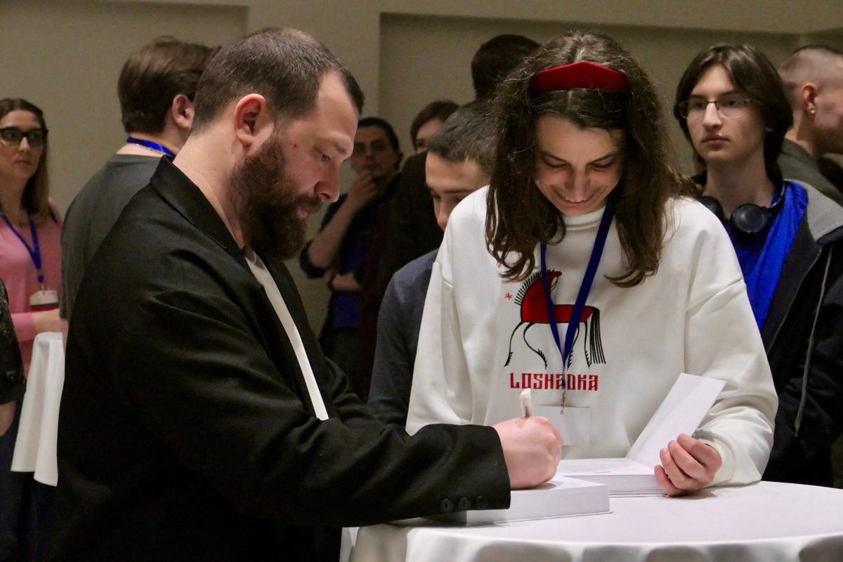 Журналист и писатель, собирающий деньги для нужд российских военных на СВО, Евгений Норин подписывает свои книги. Фото: Дарья Дмитриева / MR7