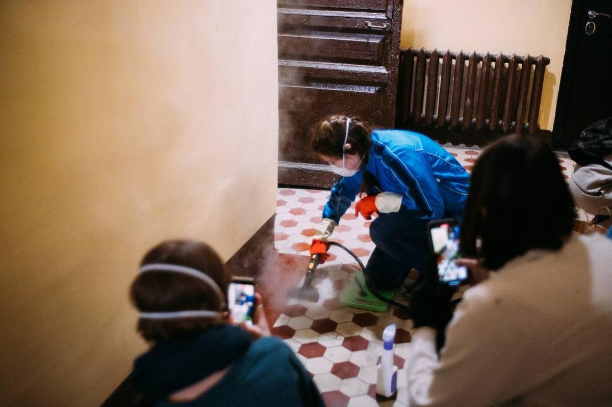 Волонтёры чистят плитку в парадной дома Александрова. Фото: Лена Ермакова / фонд «Внимание»